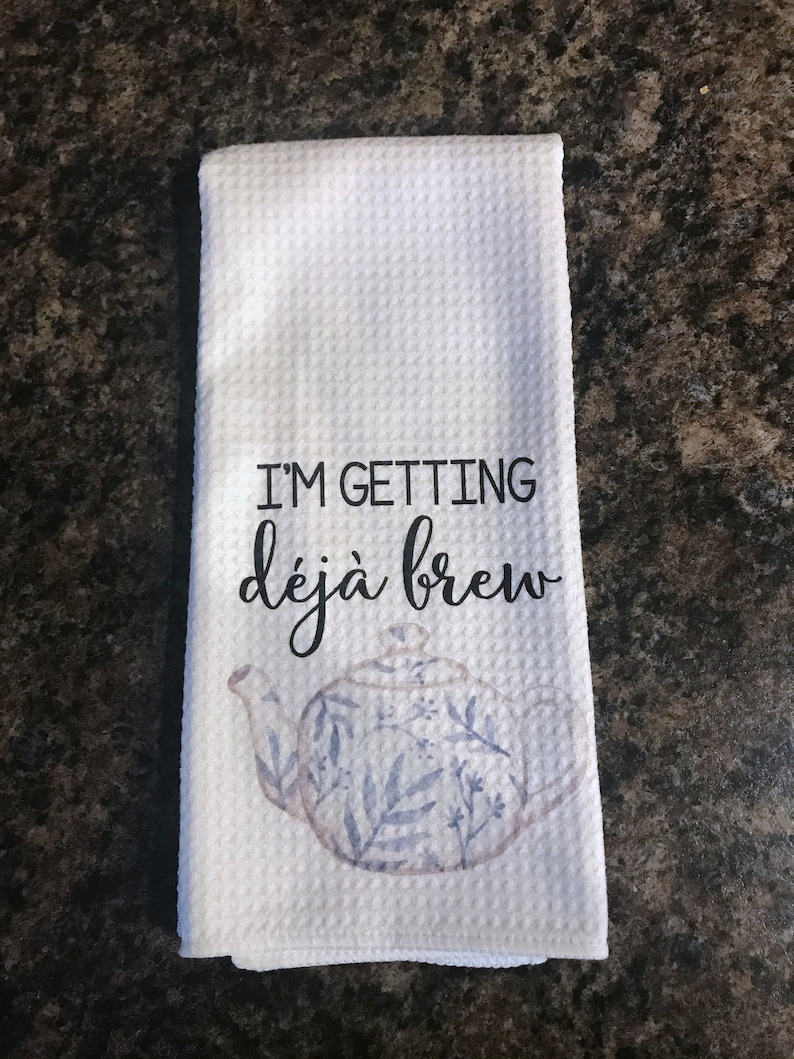 May include: White kitchen towel with a blue and white teapot design and the text "I'm getting d&eacute;j&agrave; brew".
