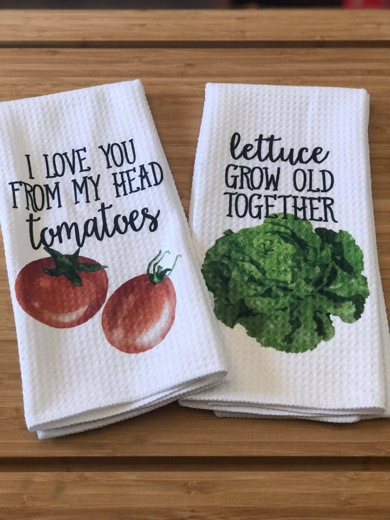 K&ouml;nnte beinhalten: Zwei wei&szlig;e K&uuml;chent&uuml;cher mit einem gr&uuml;nen Salat und roten Tomaten darauf gedruckt. Die Handt&uuml;cher haben den Text "I love you from my head tomatoes" und "lettuce grow old together" darauf gedruckt.
