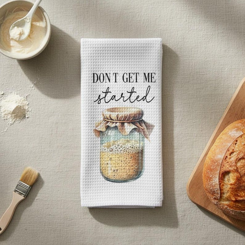 May include: White waffle-weave kitchen towel with the text "DON'T GET ME started" and an illustration of a jar. The jar is filled with a light brown substance and topped with a brown lid and a tan cloth.