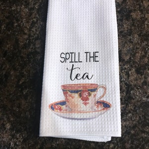 May include: White kitchen towel with the text "Spill the tea" and a vintage teacup and saucer illustration.