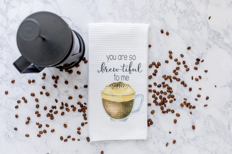 May include: White kitchen towel with a watercolor illustration of a cup of coffee and the text "You are so brew-tiful to me".