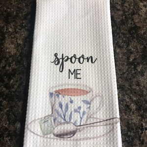 May include: White kitchen towel with the text "spoon me" and a watercolor illustration of a teacup and saucer with a spoon.