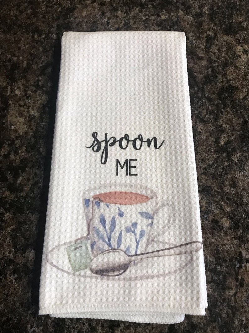 May include: White kitchen towel with the text "spoon me" and a watercolor illustration of a teacup and saucer with a spoon.