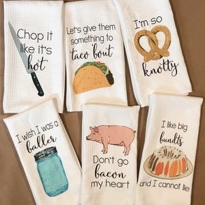May include: Set of six white kitchen towels with funny food-themed sayings and illustrations. The towels feature sayings like "Chop it like it's hot", "Let's give them something to taco 'bout", "I'm so knotty", "I wish I was a baller", "Don't go bacon my heart", and "I like big bundts and I cannot lie".