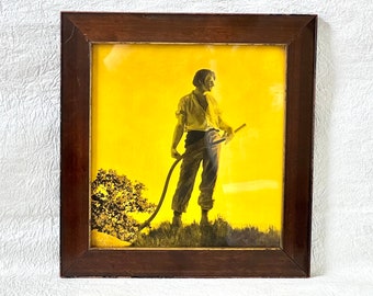 May include: A framed print of a man in silhouette standing in a field holding a stick. The background is a yellow sunset.