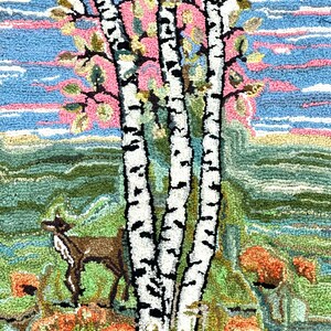 May include: A rug depicting a forest scene with three birch trees, a deer, and orange flowers. The sky is blue with pink clouds. The rug is made of yarn and has a textured surface.