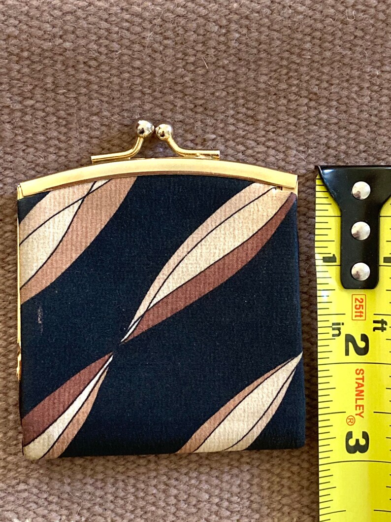 May include: A small black and brown patterned coin purse with a gold metal frame and clasp. The purse is about 3 inches wide and 2 inches tall.