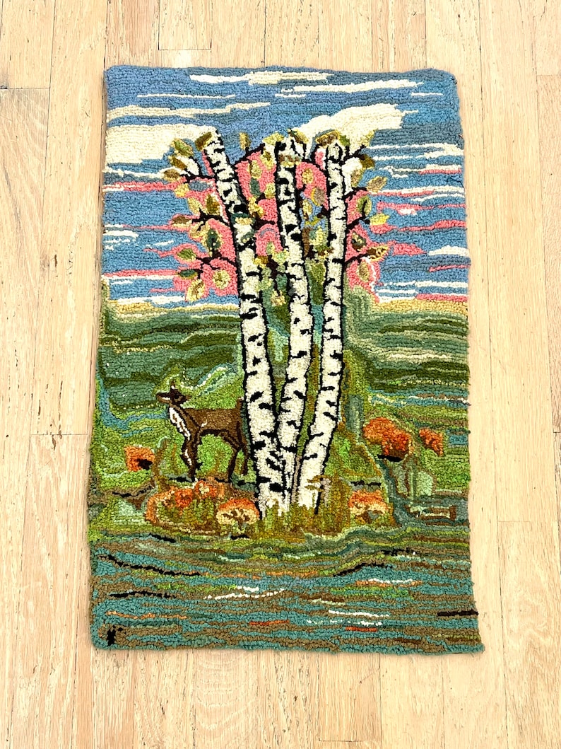 May include: A vintage hooked rug depicting a forest scene with three birch trees, a deer, and a river. The rug has a blue sky with pink clouds, green grass, and orange flowers.