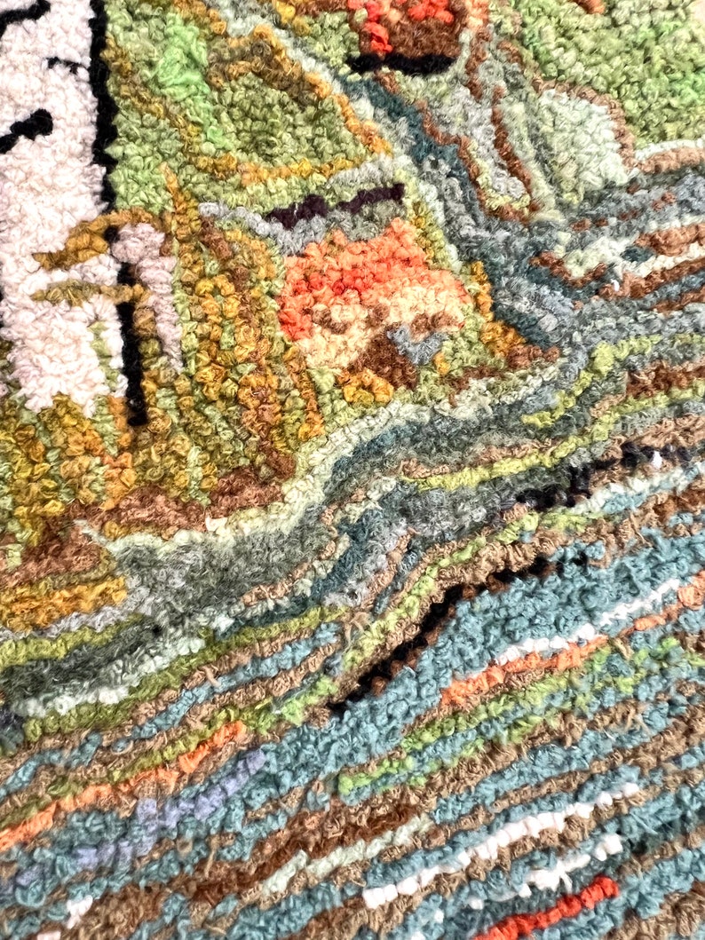 May include: Close-up of a colorful, textured rug with a variety of shades of green, brown, blue, and orange. The rug is made of looped yarn and has a unique, hand-crafted look.