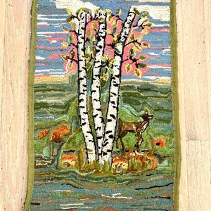 May include: A vintage hooked rug depicting a scene of three birch trees with a deer standing in front of them. The trees are white with black markings and the deer is brown. The background is a blue sky with pink clouds and a green field.