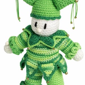 May include: A handmade crochet jester doll in shades of green and white. The doll has a pointed hat with bells, a ruffled collar, and matching trousers. Gold-coloured bells adorn the hat, sleeves, and trousers. The doll's face is white with black eyes.