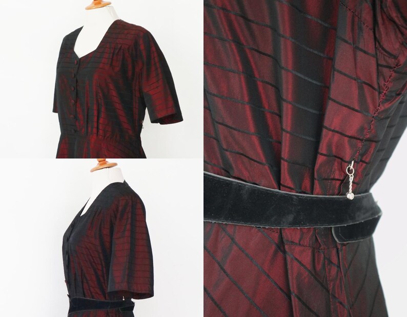 May include: A vintage dress in a deep burgundy and black striped pattern. The dress features short sleeves, a V-neck, and a black velvet belt. The fabric has a subtle sheen, and the dress is displayed on a mannequin.