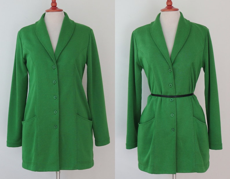 May include: A bright green long-sleeved blazer featuring a shawl collar, five matching green buttons down the front, and two front patch pockets. The garment is displayed on a mannequin, shown both without and with a thin black waist belt.