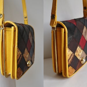 Op de afbeelding: Een vintage crossbodytas met een patchwork ontwerp. De tas heeft een gele leren frame en riem, met een sluiting. Het patchwork ontwerp bevat verschillende kleuren en texturen, waaronder zwart, bruin, rood en slangenleerpatronen.