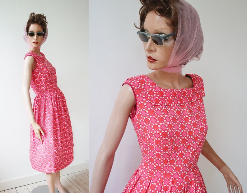 May include: A vintage-style, knee-length dress in a vibrant pink hue, adorned with a repeating geometric pattern in white and darker pink. The dress features a scoop neckline, cap sleeves, and a flared skirt. The dress is displayed on a mannequin.