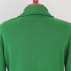 May include: A bright green knit cardigan featuring a shawl collar and long sleeves. The garment is constructed from a solid-coloured, textured knit fabric and is displayed on a red mannequin neck piece, showing the back view of the upper torso.