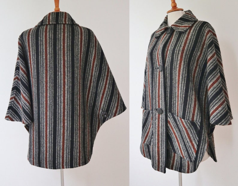 May include: A vintage cape with a striped pattern in black, gray, and rust-red. The cape features a collar, two large buttons, and two front pockets. The fabric appears to be a woven material, offering a classic, retro style.