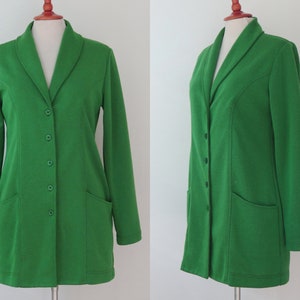 May include: A vibrant green blazer featuring a shawl collar, long sleeves, and a front button closure with four matching green buttons. The garment includes two front patch pockets and is displayed on a mannequin to show the front and side profile.
