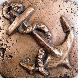 Puede incluir: Una escultura de ancla de bronce con detalles de cuerda, montada sobre un fondo texturizado marrón.