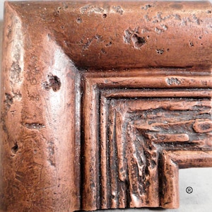 May include: Close-up of a corner of a copper-colored picture frame with a textured, distressed finish. The frame has a multi-layered design with a raised edge.