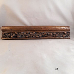 Puede incluir: Una moldura de marco de imagen de madera, de color dorado, con un diseño en relieve de piñas y ramas.