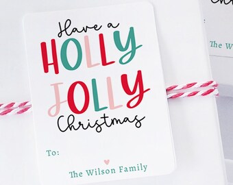 May include: White gift boxes wrapped with red and white twine, each adorned with a rectangular tag. The tags read "Have a HOLLY JOLLY Christmas" in red, green, and pink lettering. The text "The Wilson Family" is also present.
