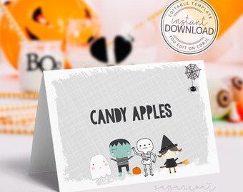 May include: A folded card with the words "CANDY APPLES" in black. The card features cartoon illustrations of a ghost, Frankenstein's monster, a skeleton, and a witch. A spider and web are in the upper right corner. The card is a Halloween theme.