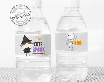 May include: Two clear water bottles with Halloween-themed labels. One label features a cartoon witch with the text "Too Cute to Spook." The other label has a skeleton with the word "BOO!" in orange. The bottles have white caps and are on a striped surface.