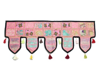 May include: A pink and green patchwork fabric door hanging with tassels. The fabric is decorated with embroidered floral patterns.