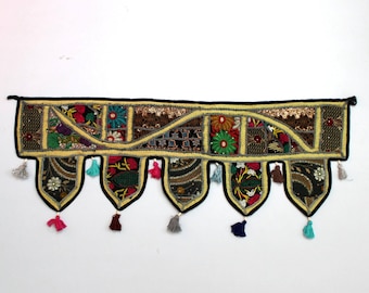May include: A colorful, handmade fabric door hanging with a patchwork design. The hanging features a black background with a yellow border and colorful fabric squares. It has a row of tassels at the bottom.
