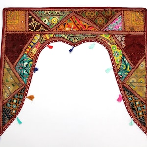 Peut inclure: Textile décoratif en patchwork dans les tons bordeaux, or et sarcelle. Le textile présente une découpe en forme de cœur avec des pompons colorés. Le design intègre des motifs géométriques et des accents miroir, créant une esthétique bohème vibrante.
