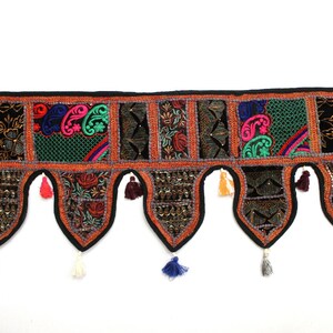 May include: A colorful, multi-patch fabric door hanging with tassels. The hanging is made of various fabrics in shades of green, red, blue, orange, and black. The fabric is decorated with embroidery and sequins.
