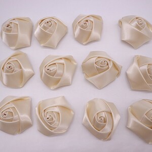 May include: Twelve ivory satin fabric rose flower embellishments. Each rose is approximately 2 inches in diameter.
