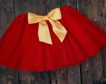 May include: A red tulle skirt with a large gold satin bow at the waist.