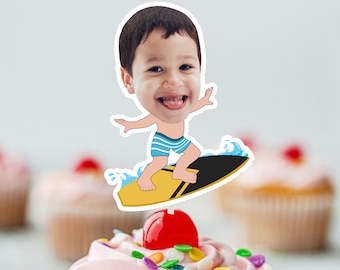 May include: A cartoon image of a boy with a big head wearing blue and white swim trunks, riding a yellow and black surfboard with a blue wave behind him. The image is printed on a cupcake topper.