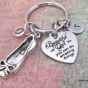 May include: Silver keychain with a heart charm that reads "Beautiful Girl you can do amazing things", a small shoe charm, and a charm with the letter "T".