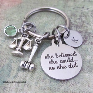May include: Silver keychain with a round charm that reads "she believed she could... so she did." Includes a gavel, scales of justice, a green gem, and a small initial charm.