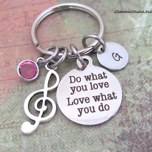 May include: Silver key chain with a pink crystal charm, a treble clef charm, and two round silver tags. One tag says "Do what you love Love what you do" and the other tag has the letter "G" engraved on it.