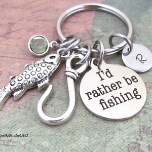May include: Silver keychain with a fish charm, a hook charm, a round charm that says "I'd rather be fishing", and a round charm with the letter "R".