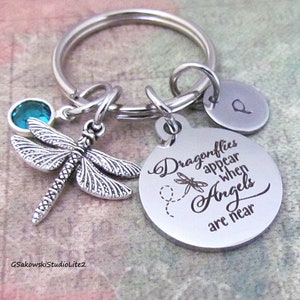May include: Silver dragonfly keychain with a blue crystal charm and a round tag that reads "Dragonflies appear when Angels are near".