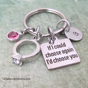 May include: Silver keychain with a ring charm, pink gem, and a tag that reads "If I could choose again I'd choose you." Includes a round charm with the letter "G".