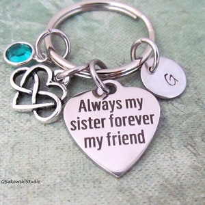 May include: Silver heart-shaped keychain with the text "Always my sister forever my friend". The keychain also features a small silver Celtic knot heart charm and a teal blue gemstone.