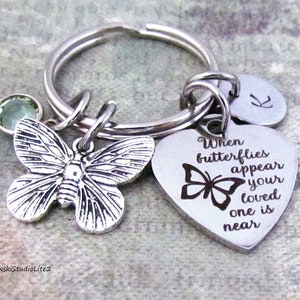 May include: Silver keychain with a heart charm that reads "When butterflies appear your loved one is near". The charm also features a small butterfly. The keychain also has a silver butterfly charm and a green crystal charm.