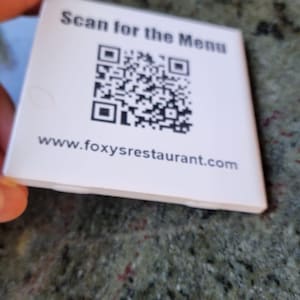 May include: A white ceramic mug with a black handle and the text "But First, Coffee" in a black, bold font. The mug is on a white surface. The mug is 10 cm tall.