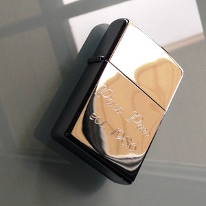 May include: A silver lighter with an engraved inscription that reads "Paw Paw est. 1986".