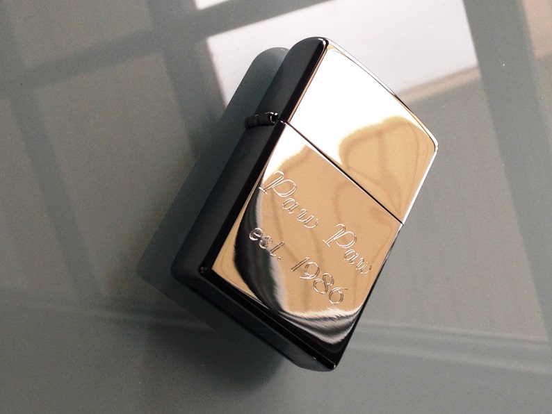 May include: A silver lighter with an engraved inscription that reads "Paw Paw est. 1986".