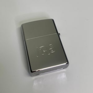 May include: A silver lighter with the initials "J.R.S." engraved on the front.
