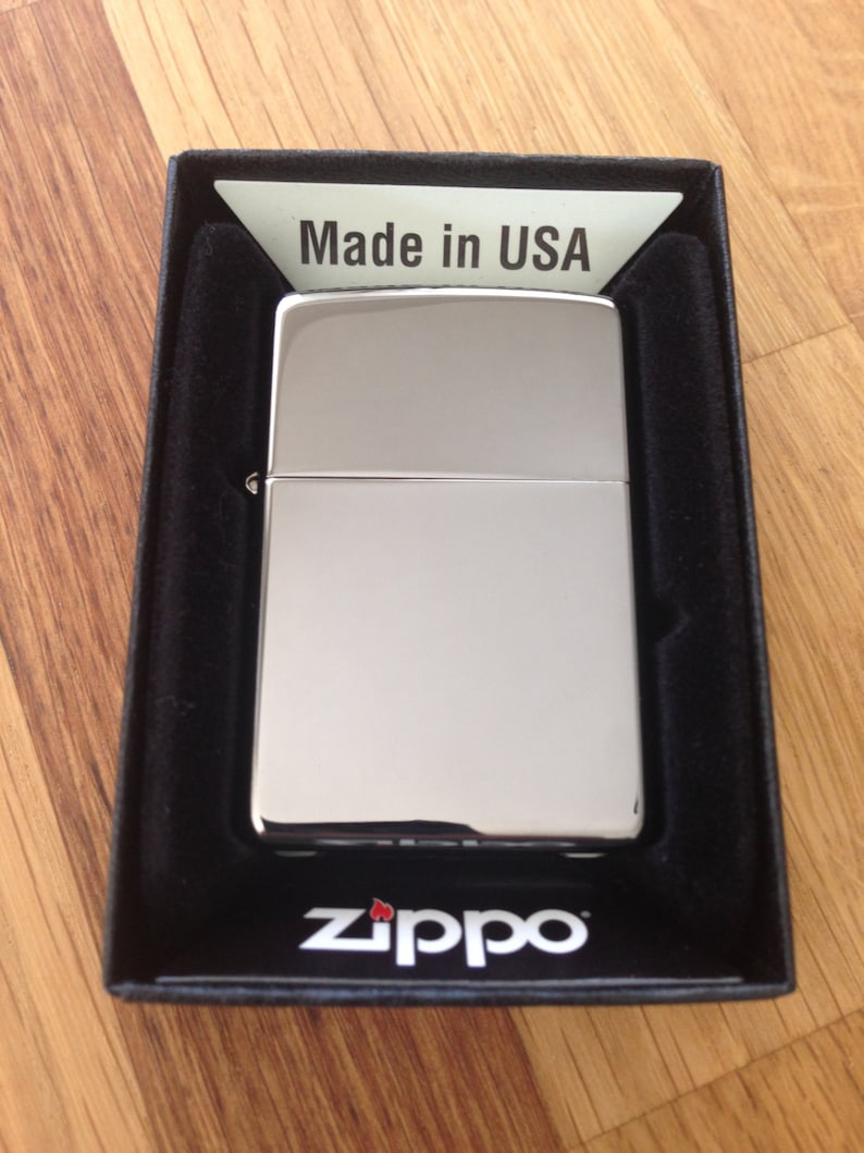 May include: A silver Zippo lighter in a black box with the words "Made in USA" and "Zippo" printed on it.