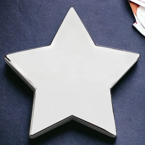 May include: A silver star-shaped dish with a smooth, reflective surface.
