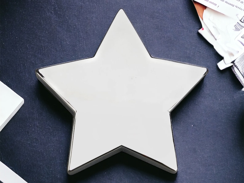 May include: A silver star-shaped dish with a smooth, reflective surface.